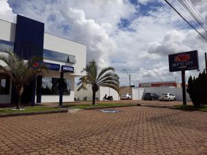a shopping center with palm trees in front of a building at Bravo City Hotel Primavera in Primavera do Leste