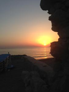 a sunset over the ocean with a person looking out from a cliff at Asterias Studios & Apartments in Kalyves