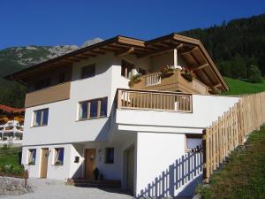 a white house with a balcony on a hill at Haus Harbauer in Neustift im Stubaital