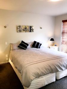 una camera da letto con un grande letto bianco con cuscini neri di Lavender Hill a Riverhead