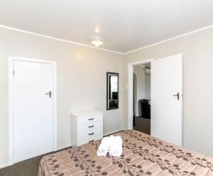 a bedroom with a bed with two white shoes on it at Flamingo Motel in New Plymouth