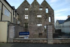 un antiguo edificio de piedra con una valla delante en Castle Inn, en Newtownstewart