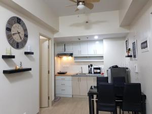 a kitchen with white cabinets and a clock on the wall at Suntrust Parkview Apartment in Manila