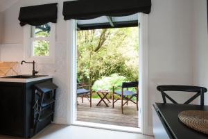 a kitchen with a door open to a patio with chairs at Leddicott Cottage in Olinda