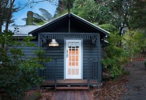 a black out house with a white door at Leddicott Cottage in Olinda