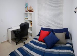 Schlafzimmer mit einem Bett mit bunten Kissen und einem Schreibtisch in der Unterkunft MoradiaSP - Apartamento Novo Completo 650 M do Metro Guilhermina in São Paulo