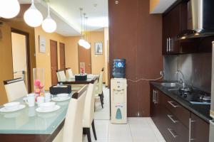 a kitchen with a table with a tv on the wall at Antique 3BR at Grand Setiabudi Apartment By Travelio in Bandung +14 photos