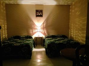 a room with two beds and a light on the wall at Hotel Lienzo Charro 1 in Huasca de Ocampo