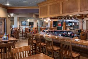 Oacoma的住宿－Arrowwood Resort at Cedar Shore，餐厅设有酒吧,配有木桌和椅子