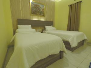 1 dormitorio con 2 camas con sábanas blancas en Muara Inn ternate en Ternate
