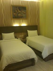 1 Schlafzimmer mit 2 Betten und weißer Bettwäsche in der Unterkunft Muara Inn ternate in Ternate