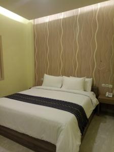 1 dormitorio con 1 cama grande con almohadas blancas en Muara Inn ternate en Ternate