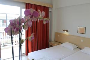 a bed room with a white bedspread and a pink flower vase at Hotel Savoy in Rhodes Town