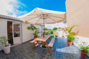 eine Terrasse mit einem Holztisch und einem Sonnenschirm in der Unterkunft Le Palmier de la Paix in Le Tampon