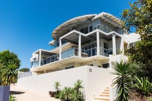 a large white building with palm trees in front of it at Indulge at Iluka, Castaways Beach in Marcus Beach