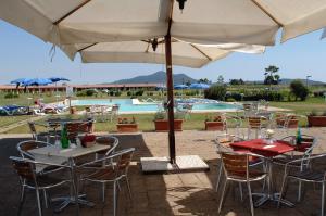 a group of tables and chairs with an umbrella at Residenza Principina in Principina Terra