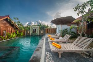 a swimming pool with lounge chairs and an umbrella at The Lebak Canggu in Canggu
