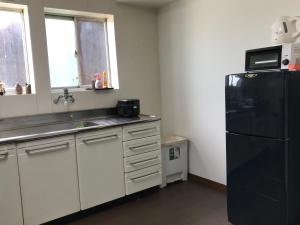 uma cozinha com um frigorífico preto e um lavatório em Guesthouse En em Omihachiman