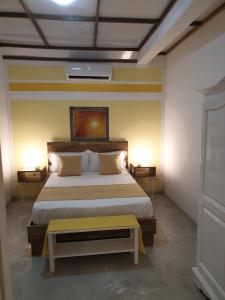 a bedroom with a large bed with a yellow bench at Casa Frangipani Mauritius in Trou dʼ Eau Douce