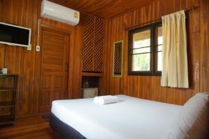 a bedroom with a white bed and a window at Samnaree Garden House in Ban Phae Mai