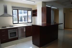 a kitchen with brown cabinets and a window at Palm Beach Hotel Dili in Dili