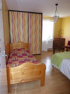 a bedroom with a wooden bed and a striped wall at Gîte de la Côte in Viéville