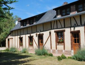 un grand bâtiment avec un toit noir et des fenêtres dans l'établissement Chambres d'hôtes La Petite Flambée, à Le Tronquay