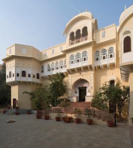 un gran edificio con macetas en un patio en Alsisar Mahal- Heritage Hotel, en Alsīsar