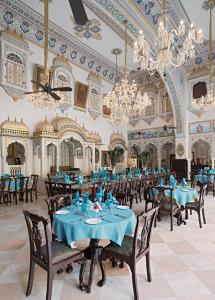 un comedor con mesas y sillas azules y lámparas de araña en Alsisar Mahal- Heritage Hotel, en Alsīsar