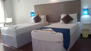 a hotel room with two beds and a stool at Flyzone Seashell Cottages Only For Indian Nationals with valid entry permit in Agatti