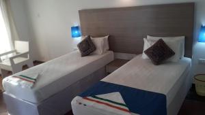 a bedroom with two beds and a chair at Flyzone Seashell Cottages Only For Indian Nationals with valid entry permit in Agatti
