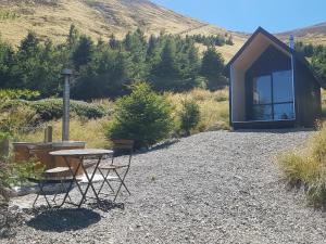 einem Picknicktisch und Stühlen vor einer Hütte in der Unterkunft Lake Stella Mountain Huts in Mt Lyford