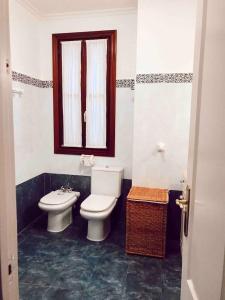a bathroom with a toilet and a sink and a window at Apartamento en el autentico corazón de Mundaka in Mundaka