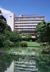 a building in front of a pond in front of a building at Hotel Garden Square Shizuoka in Shizuoka