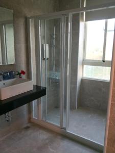 a glass shower in a bathroom with a sink at Full Moon Resort in Hengchun