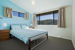 a bedroom with a bed and a large window at Grantys House in Merimbula