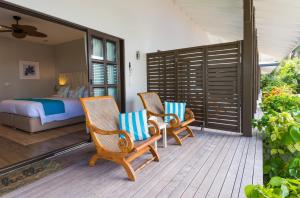a bedroom with two chairs and a bed on a porch at Le Nautique Waterfront Hotel La Digue in La Digue