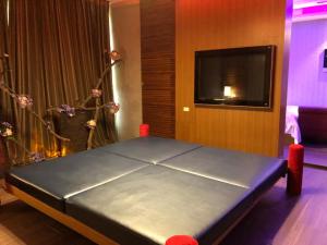 Cama en habitación con TV en la pared en Idee SPA Motel en Yangmei