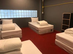 een kamer met 3 matrassen op een rode vloer bij 248 STREET HOSTEL in Chiang Mai