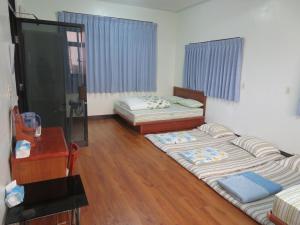 three beds in a room with wooden floors and a table at Hoin 4 in Xigang