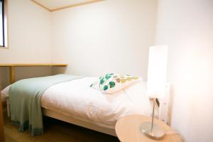 1 dormitorio con 1 cama y 1 mesa con lámpara en Atami Ajiro House貸切温泉宿, en Atami