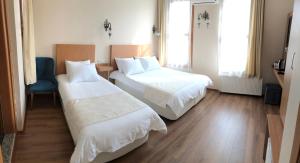a hotel room with two beds and a chair at Ottoman's Pearl Hotel in Istanbul