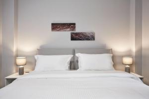 1 Schlafzimmer mit 2 weißen Betten und 2 Gemälden in der Unterkunft Charming Studio Apartment in Athen