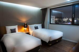 a hotel room with two beds and a window at Amanti Hotel Seoul in Seoul