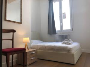 1 dormitorio con 2 camas, silla y ventana en San Frediano Apartment, en Florencia