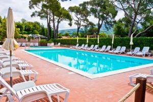 a pool with chaise lounge chairs and an umbrella at Borgo di Pomaia in Pomaia