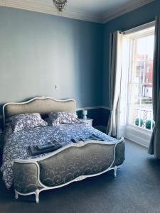 a bedroom with a bed with blue walls and a window at Regency Rooms Guesthouse in Cheltenham