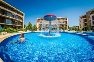 een jonge jongen in een zwembad met een fontein bij Waterpark Fort Apartments in Sunny Beach