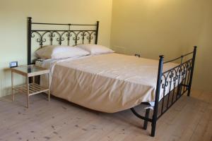 a bedroom with a bed with a black frame and a table at Sa Domu Beccia B&B in Uras
