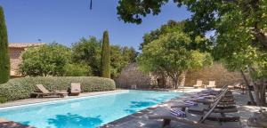 a swimming pool with lounge chairs next to a brick wall at Le Jas de Gordes in Gordes